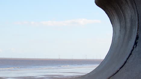 ingoldmells, playa de skegness enmarcada por defensas marinas en un día frío de invierno con turbinas eólicas en la distancia