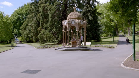 static shot of a mother and her kids playing while another lady walking on a road in the lst park on a sunny day