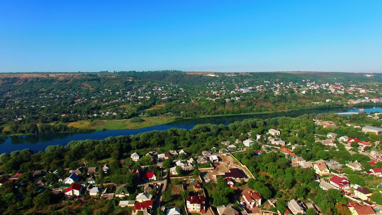 Landscape of a beautiful large village locating on the picturesque bank of the river. Amazing blue clear sky at backdrop. Top view.