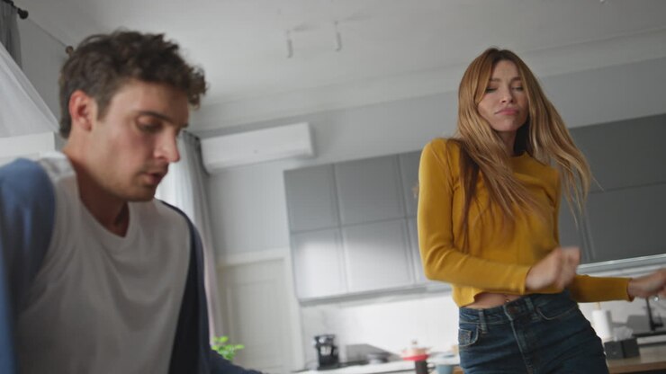 Donna spensierata che balla e si gode il weekend a casa, primo piano. Coppia che si diverte.