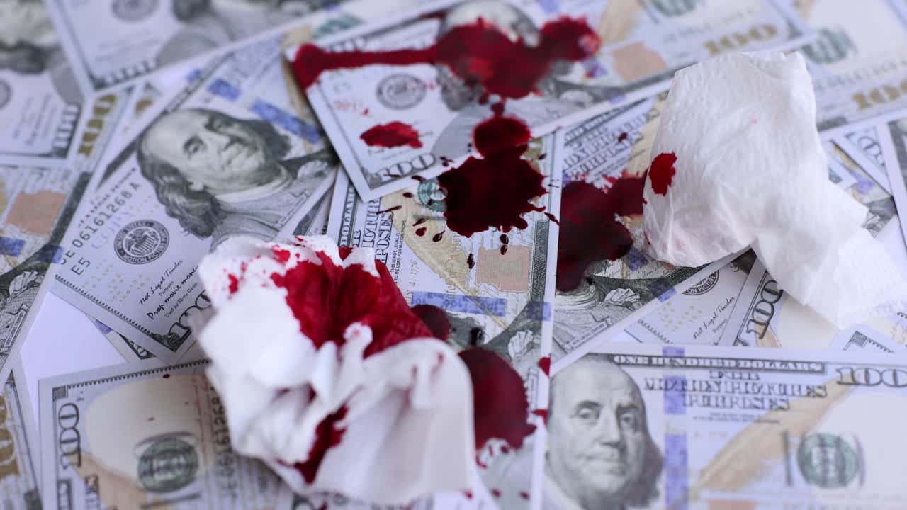 Drops of dark red blood fall on scattered money and napkins