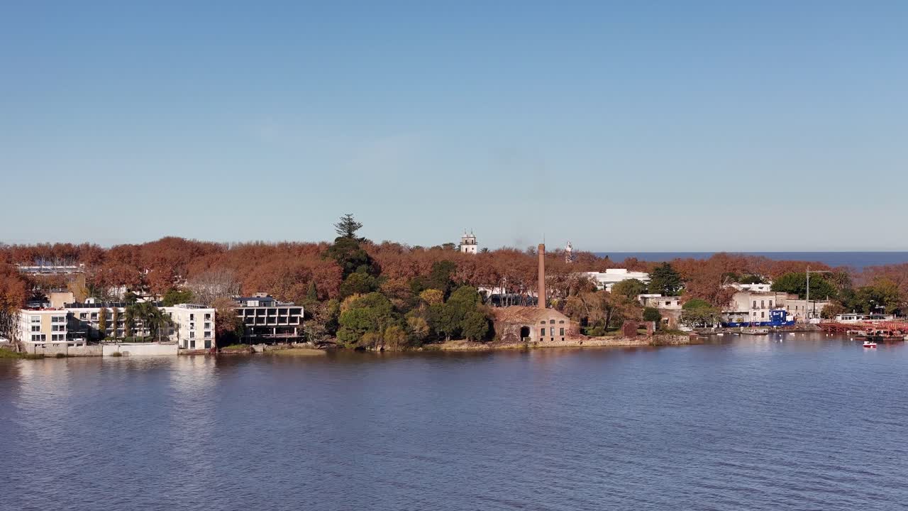 Drone shot over the bay of Colonia del Sacramento, Uruguay. Clear winter morning with blue sky. Visible: Bastión del Carmen, lighthouse, church and boats on the river