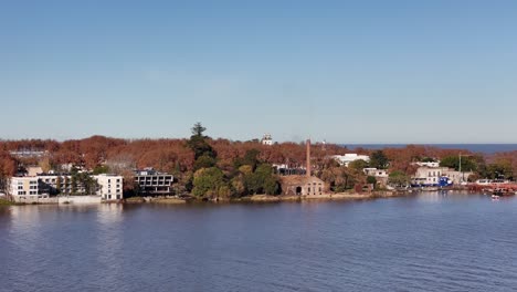 drone shot over the bay of colonia del sacramento, uruguay. clear winter morning with blue sky. visible: bastión del carmen, lighthouse, church and boats on the river