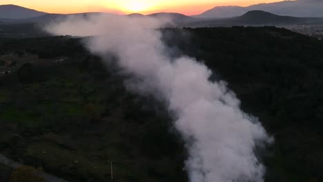 vuelo con un dron en el lado de una colina donde se puede ver un gran rastro de humo que se mueve rápidamente en el fondo hiperlapso tenemos una puesta de sol amarillo rojizo en el valle de tietar, provincia de ávila