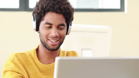 Smiling-man-with-headphones-using-laptop-