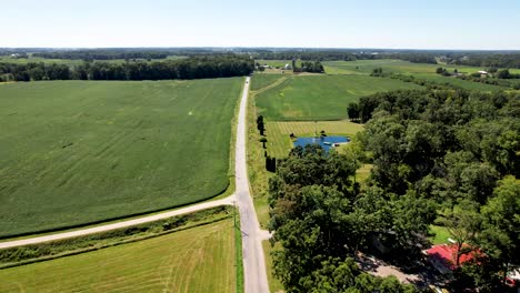 Felder-Auf-Dem-Bauernhof-Im-Mittleren-Westen-Der-USA-Mit-Einem-Auto,-Das-Eine-Lange,-Gerade-Straße-Hinunterfährt