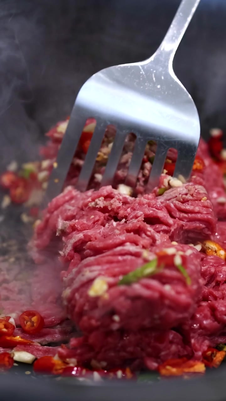 Daging sapi ditumis dengan sayuran di wajan, menampilkan warna-warna cerah dan proses memasak yang dinamis