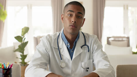 Biracial-male-doctor-making-video-call-in-bright-room,-slow-motion