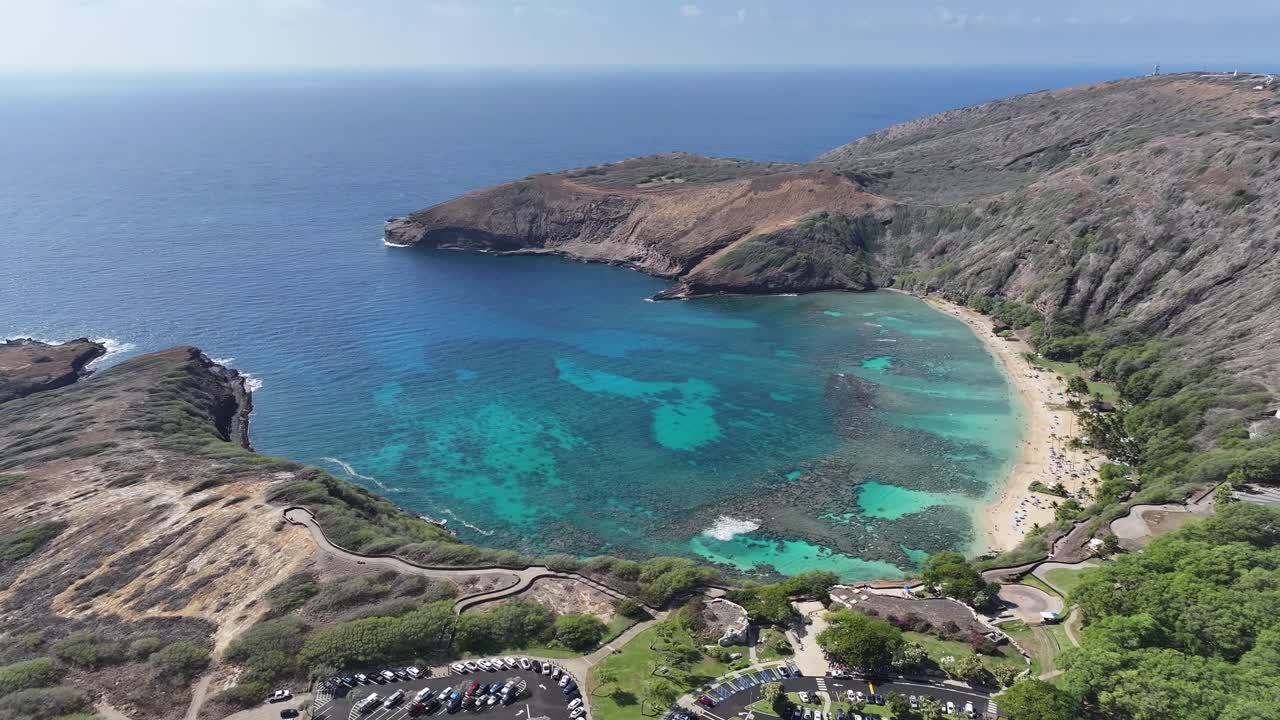 Aerial drone footage over Hanauma Bay on Oahu, Hawaii, showcasing turquoise waters, coral reefs, sandy beaches, tropical coastline, and lush vegetation along this iconic island snorkeling destination