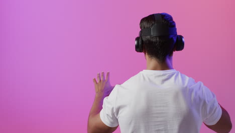 video de un hombre biracial usando auriculares vr en un fondo rosa y púrpura