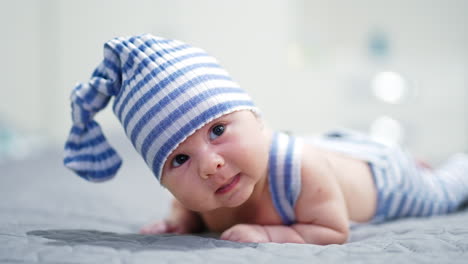 sweet kid in funny striped suit lies on his belly. lovely boy trying to keep his head up. close up.