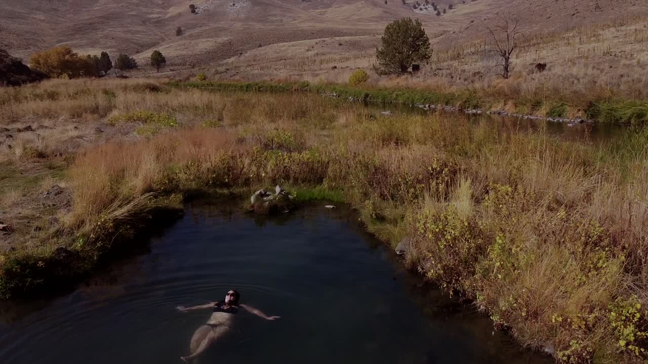 비행 드론은 검은색 비키니를 입은 온천에 있는 여성의 공중 전망을 촬영했습니다.