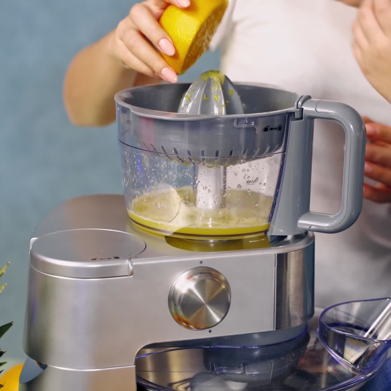 Mother and daughter doing fresh orange juice together. Woman and a little girl making orange drink in the squeezer machine on the table.