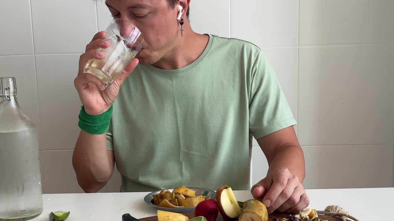 Uomo che mangia frutta fresca e beve acqua a un tavolo