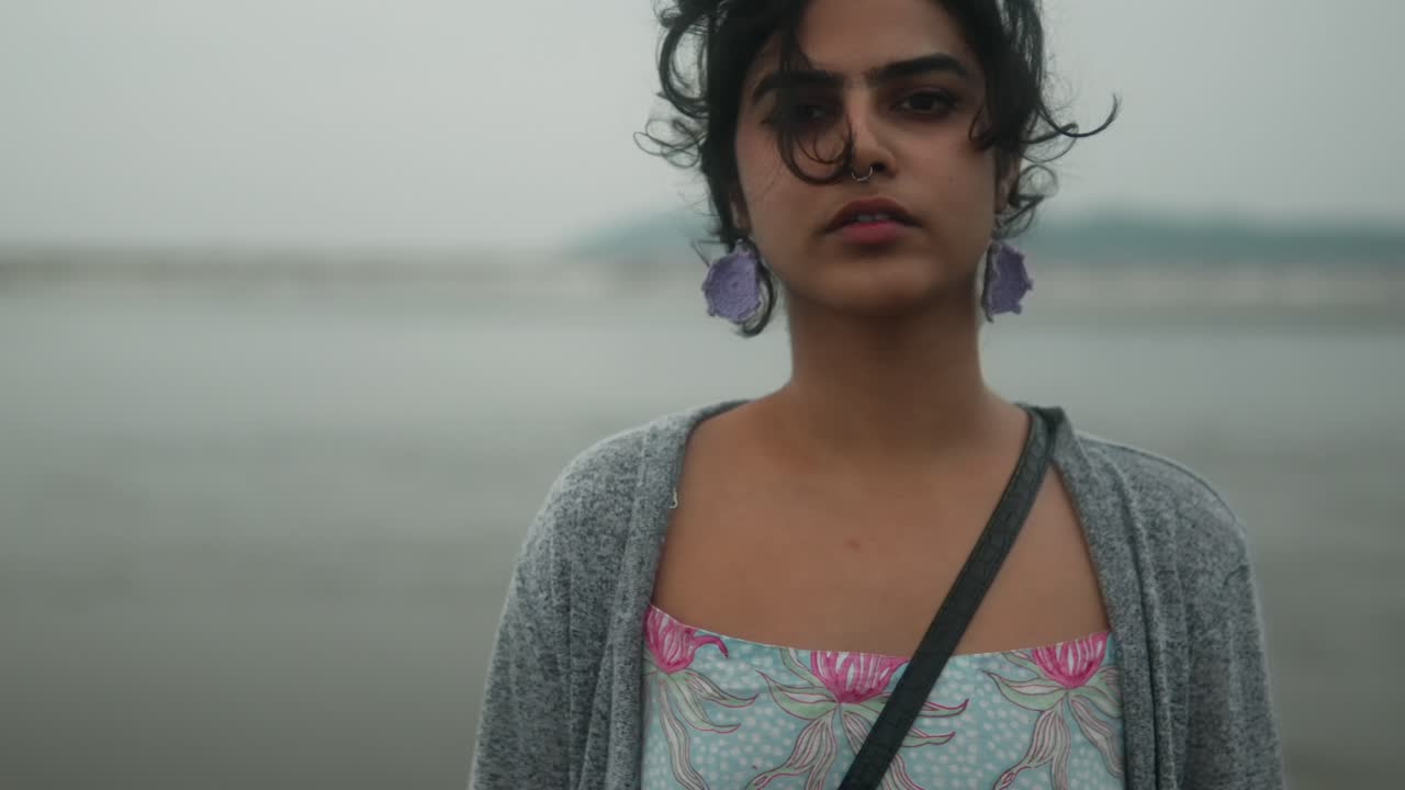 retrato de una mujer joven con su cabello en el viento con una mirada profunda y penetrante en la playa