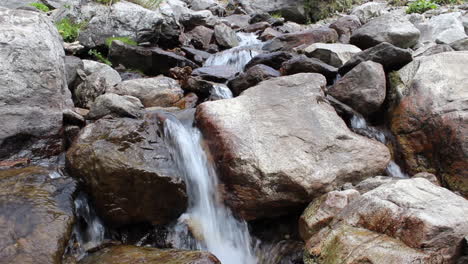 Rippling-stream-is-flowing-between-rocks-and-grass