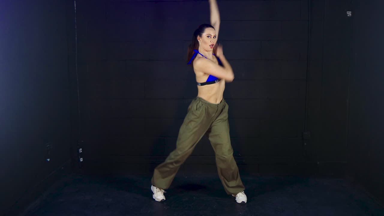 bailarina urbana de moda de longitud completa que realiza una intensa creatividad de baile enérgico en el rendimiento del estudio