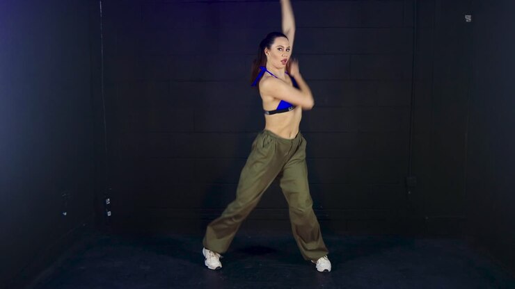 Full length fashionable female urban dancer performing intense energetic dancing creativeness in studio performance