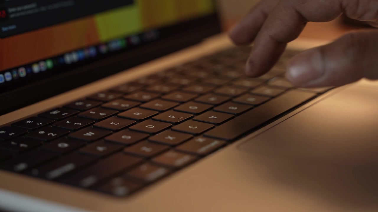 Hands Typing on Laptop Keyboard in Warm Cozy Lighted Room.