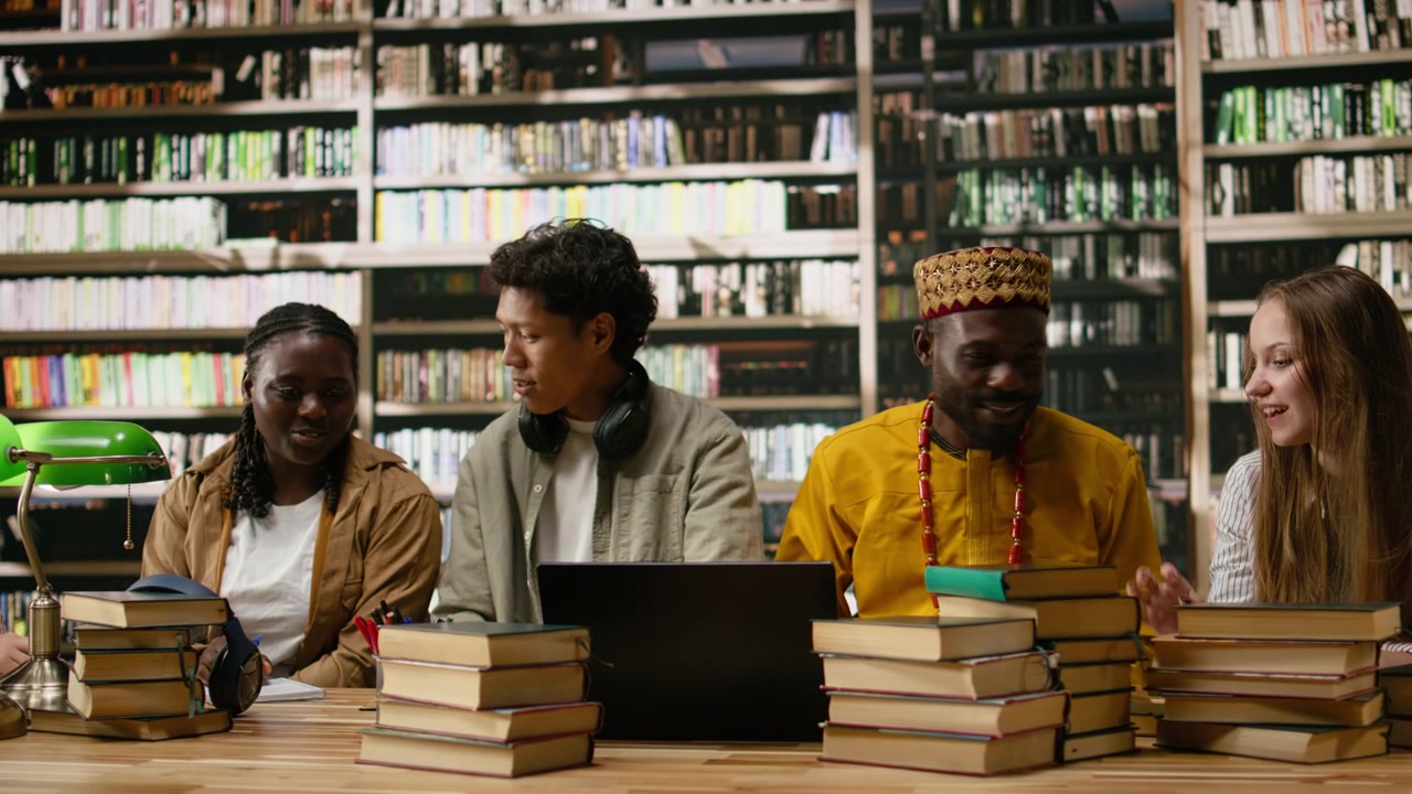 Diverse students discuss classwork during group study around library table