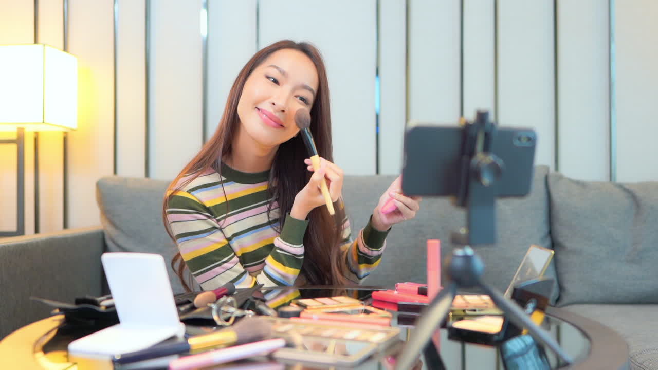 Ragazza asiatica vlogger che registra un tutorial di make-up cosmetico con lo smartphone