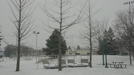 árboles sin hojas con mesa de picnic en un banco del parque vacío en invierno con nieve