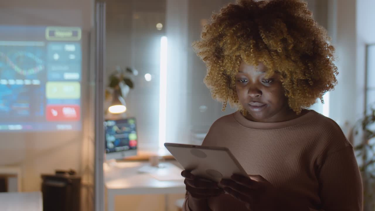 African American Woman Working on Tablet in Office at Night