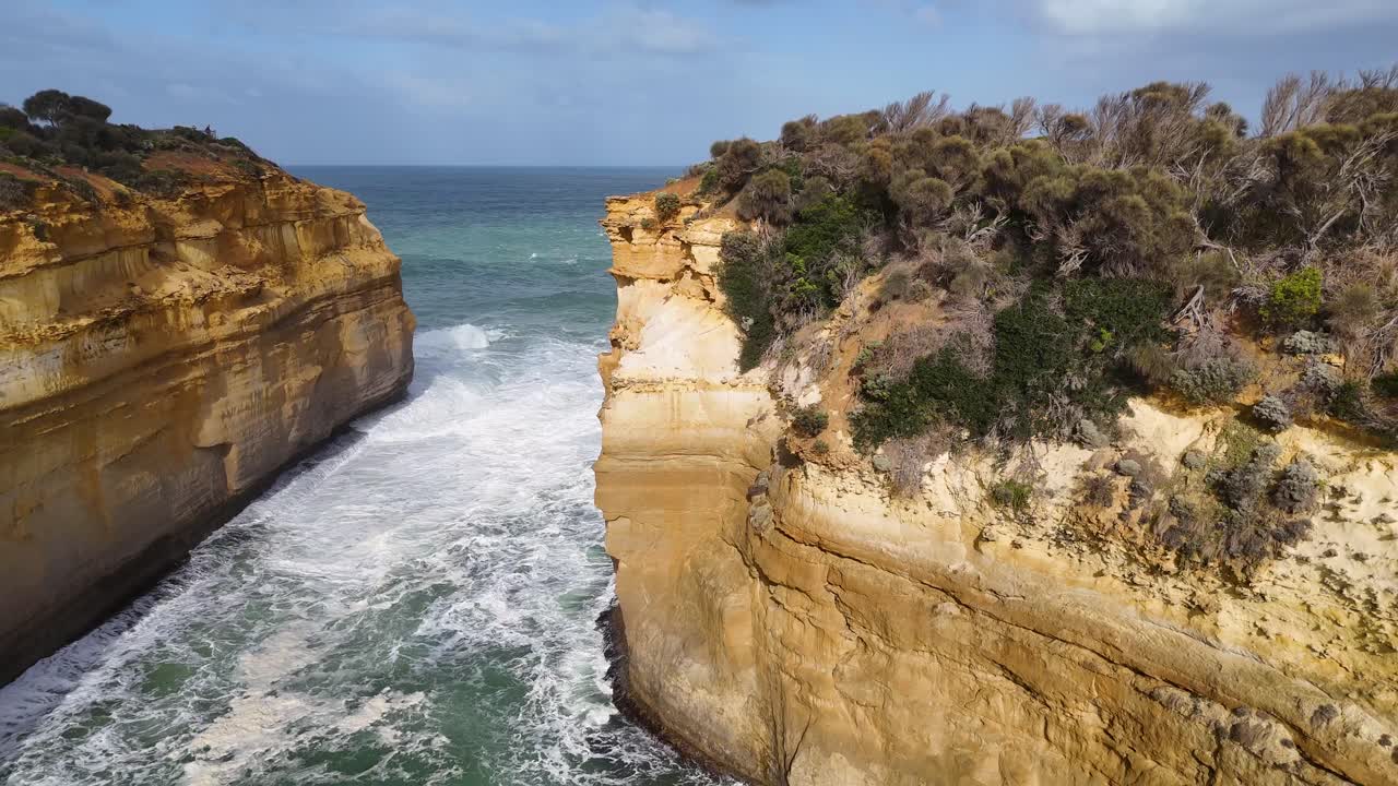 Aerial footage captures the rugged cliffs and turquoise waters of Loch Ard Gorge under bright daylight