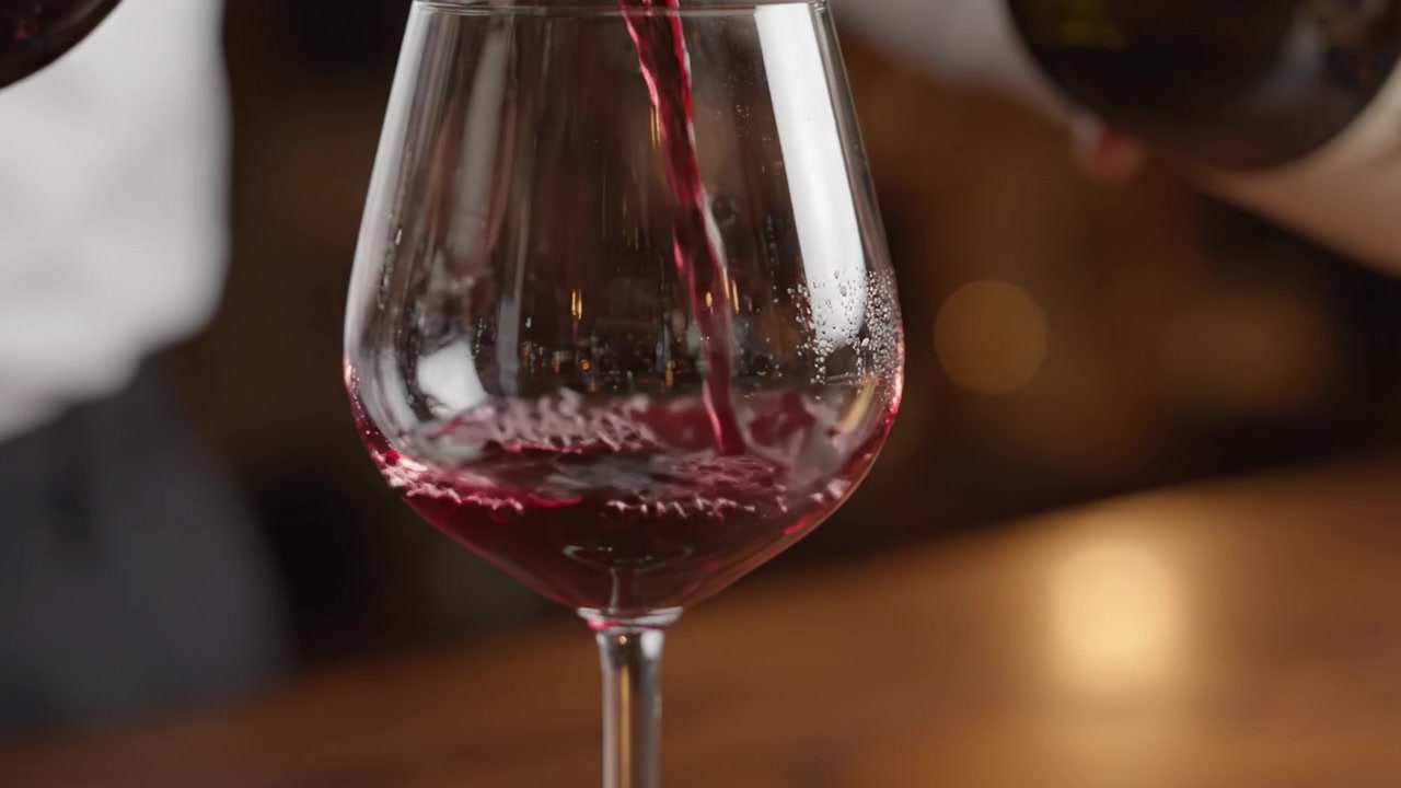 Vertiendo Vino Tinto en una Copa: Capturando el Arte del Servicio del Vino en un Entorno Sofisticado con Burbujas Brillantes y una Rica Coloración