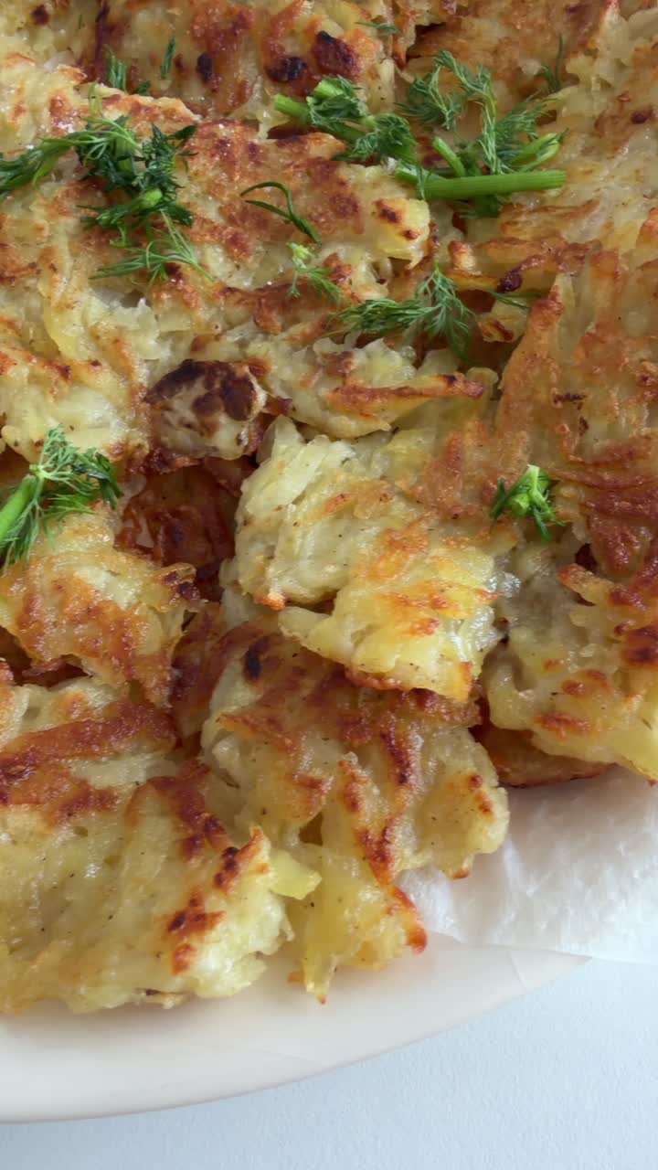 Primo piano di frittelle di patate dorate guarnite con aneto fresco.