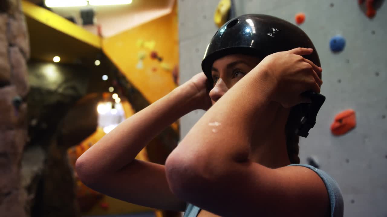 인공 벽 4k를 오르기 전에 안전 헬 ⁇ 을 착용 한 여성