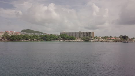 a drone shot pans across the calm water towards the shoreline of curaçao