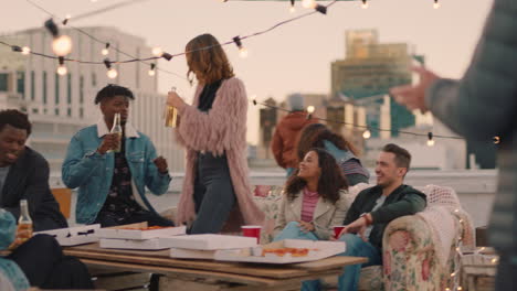 group of happy friends hanging out dancing together enjoying rooftop party at sunset drinking alcohol having fun on weekend celebration