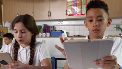 pupils sitting at desks using digital tablets shot on r3d