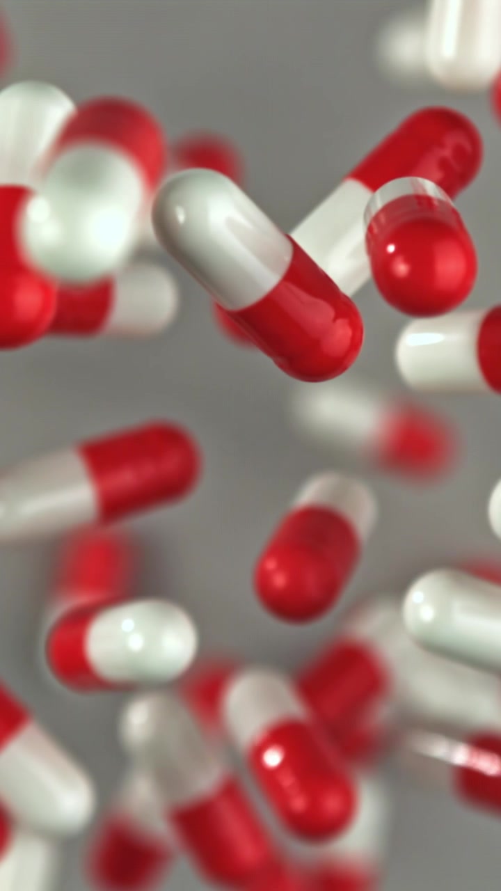 Capsule farmaceutiche rosse e bianche galleggianti al rallentatore