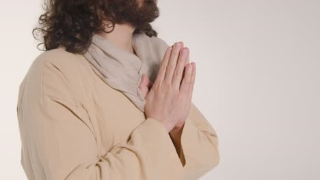 close up shot of man wearing robes with long hair and beard representing figure of jesus christ praying 2