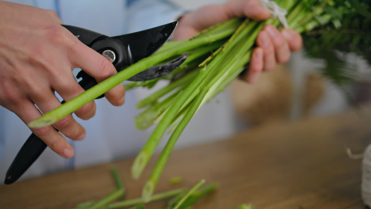 Closeup floristic hands cut flower stem on flower shop table. Floristry concept