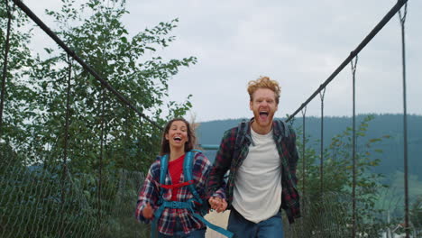 two backpackers racing nature on mountain countryside. smiling couple hold hands