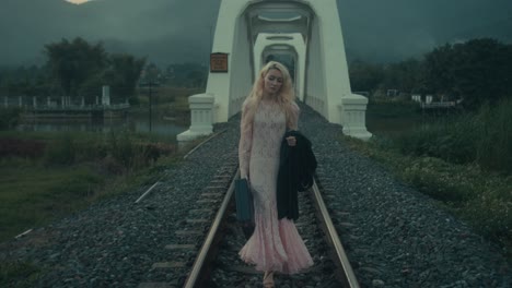 woman walking on train tracks by a bridge