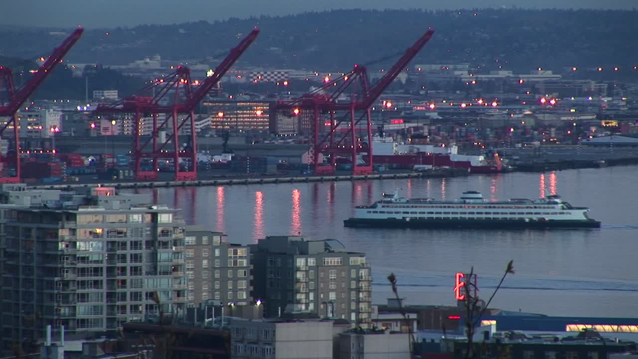 유람선은 창고 드라이독과 건물로 둘러싸인 시애틀 항구를 통과합니다.
