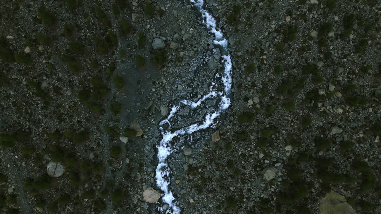 vista aérea de arriba hacia abajo de una corriente de agua que fluye en el lecho seco de un río de montaña en el alpe ventina de valmalenco en el norte de italia