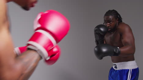 tomada de estudio de acción en tiempo real de dos boxeadores masculinos con guantes luchando en un combate de boxeo contra un fondo gris 5