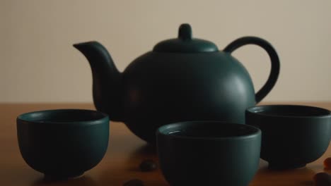 minimal background of a green japanese tea set with steam coming out of the cups, on a wooden table, with some stones around