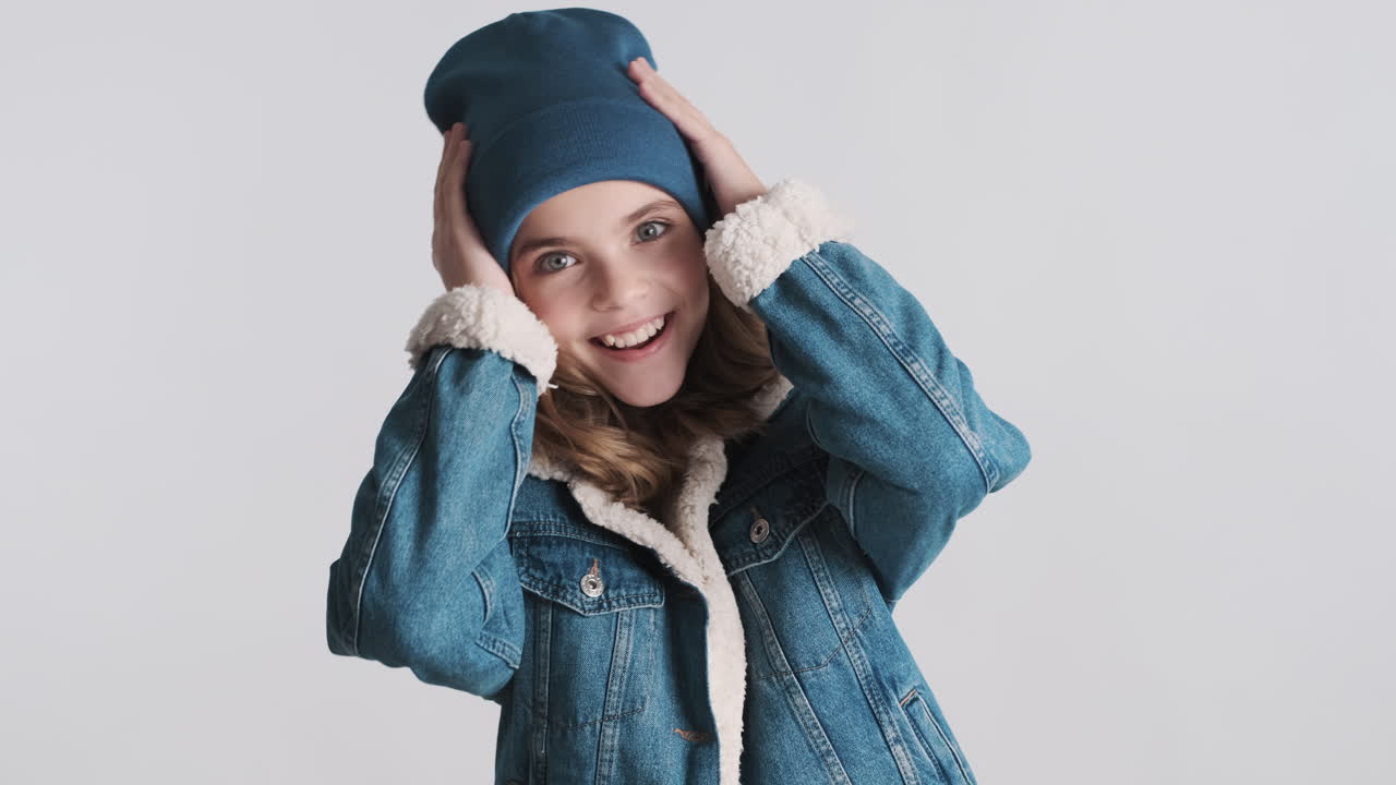 Surprised teenage Caucasian girl wearing denim jacket and beanie.