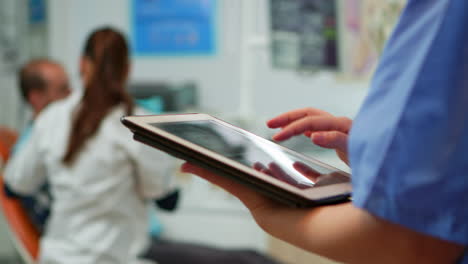 close up of nurse holding and typing on tablet