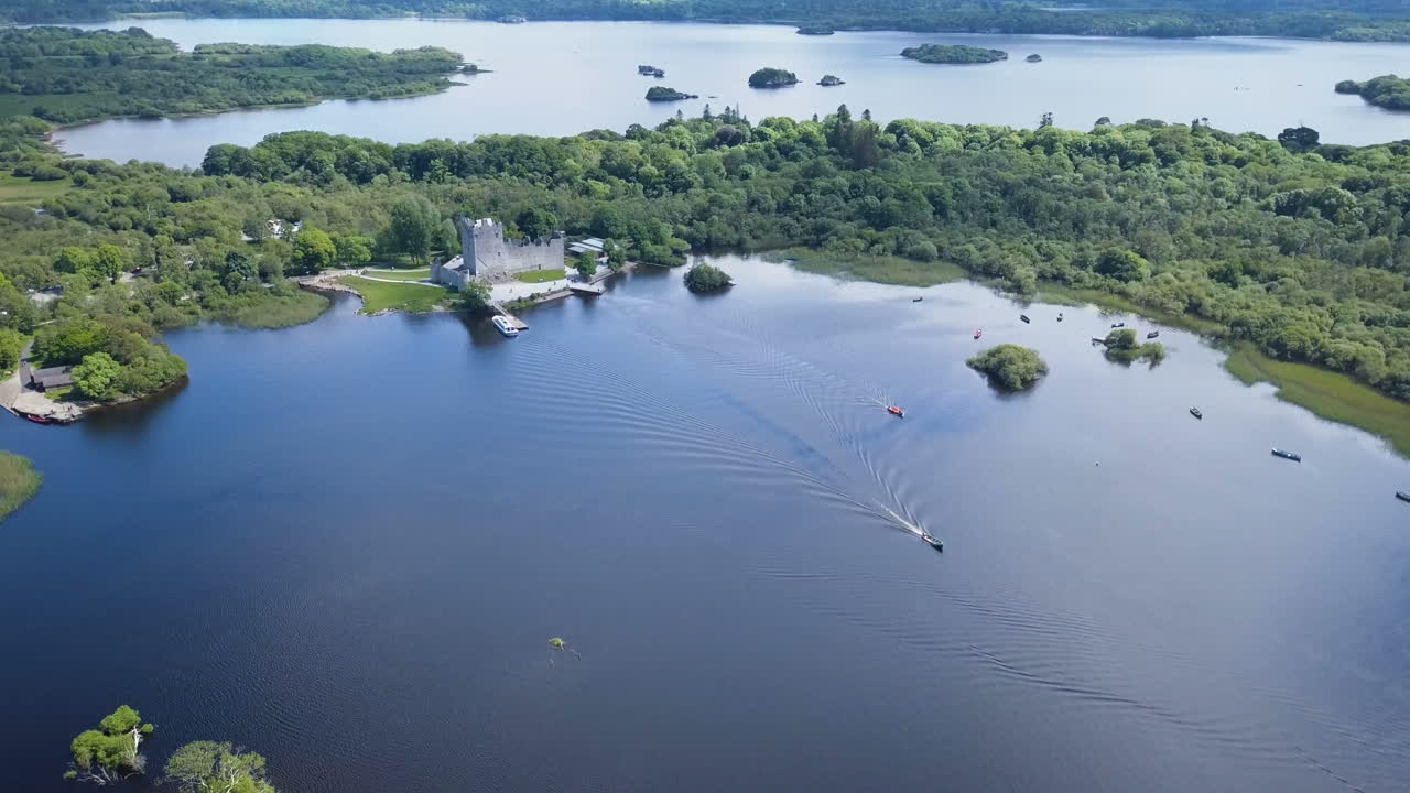 video aéreo en movimiento sobre un gran lago hermoso, con pequeñas embarcaciones de recreo saliendo de un antiguo castillo junto a la costa