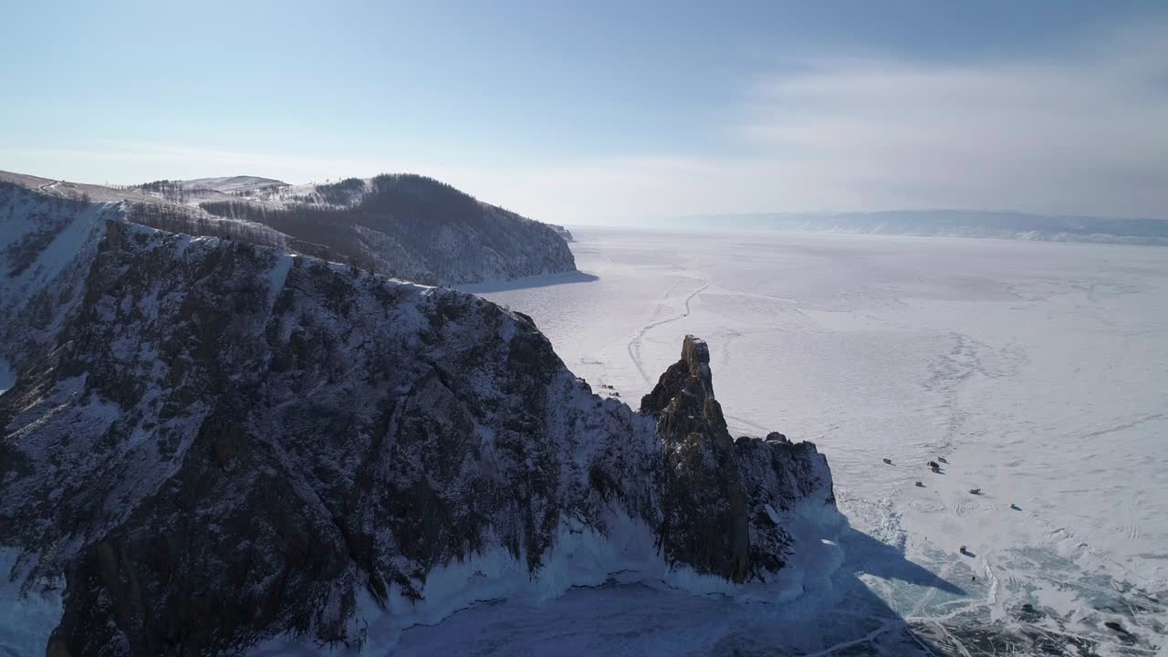 vista aérea del cabo khoboy, isla de olkhon. rocas altas en el lago congelado baikal con mucha gente y coches alrededor. destino turístico popular. paisaje de invierno. vista panorámica