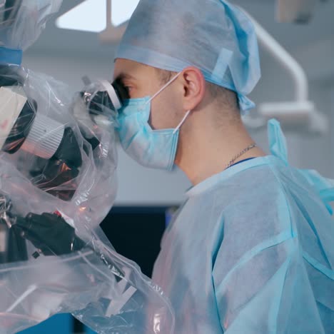 doctors use medical equipment in operating theater. surgeons in blue medical uniform and safety mask look into the modern microscope during surgery.