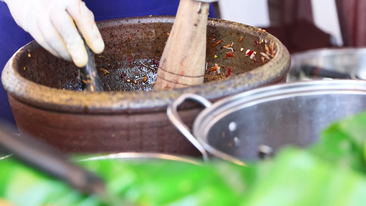 Hands making papaya salad using mortar and pestle in Thailand