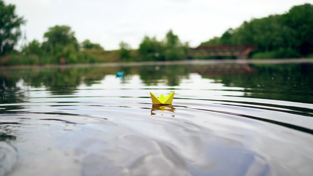 A paper ship floating in the river on the waves. Origami Paper Boat